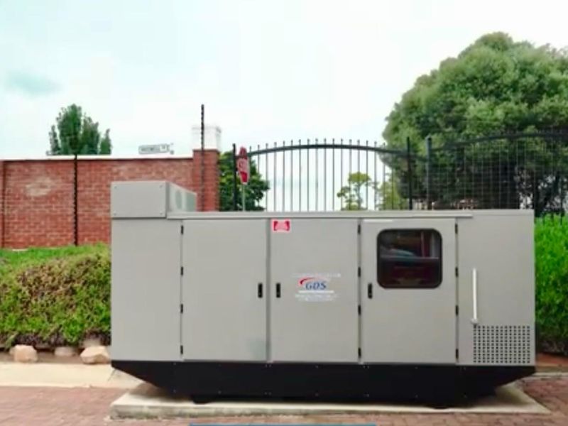 A commercial-grade backup power generator unit installed on a concrete pad within the property grounds.