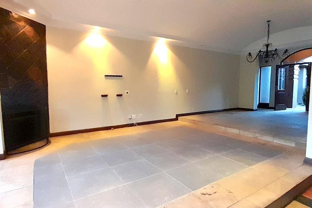 Spacious living area featuring a sunken floor design, built-in fireplace with decorative tiling, and recessed lighting, leading to an adjacent hallway.