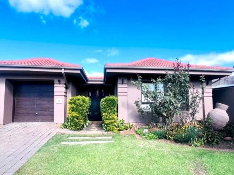 Front elevation of a single-story house featuring a tiled roof, paved driveway, integrated garage, and a landscaped front garden.