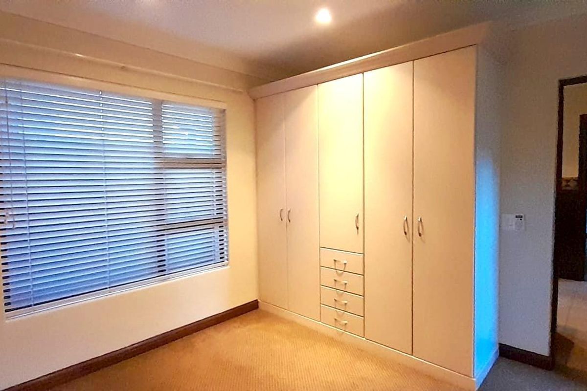 A bedroom featuring built-in cabinetry with integrated drawers and horizontal window blinds, providing functional storage and natural light control.