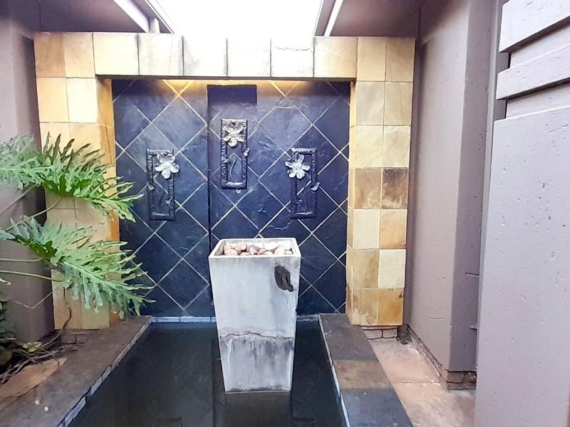 A decorative outdoor water feature with stone cladding and integrated lighting, set within a private courtyard area.
