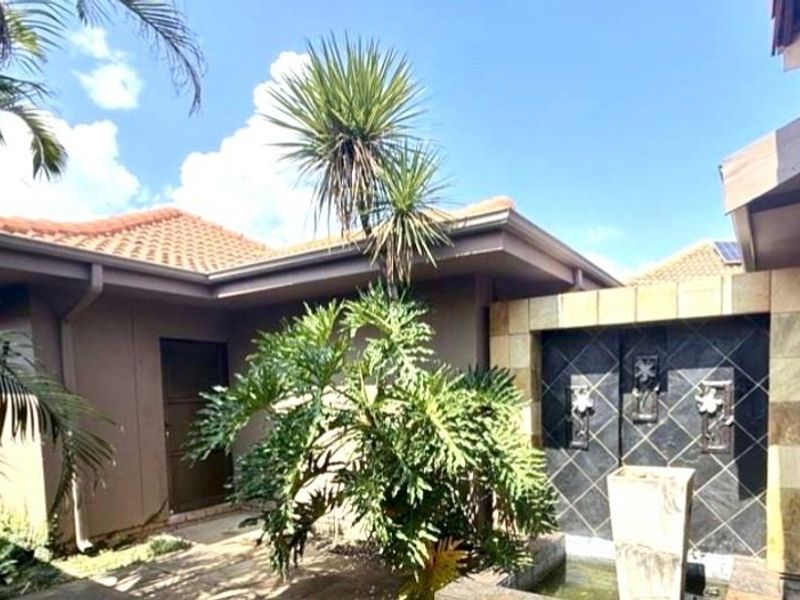 A well-maintained exterior courtyard area featuring a decorative tiled water feature, established landscaping, and terracotta roof tiles.