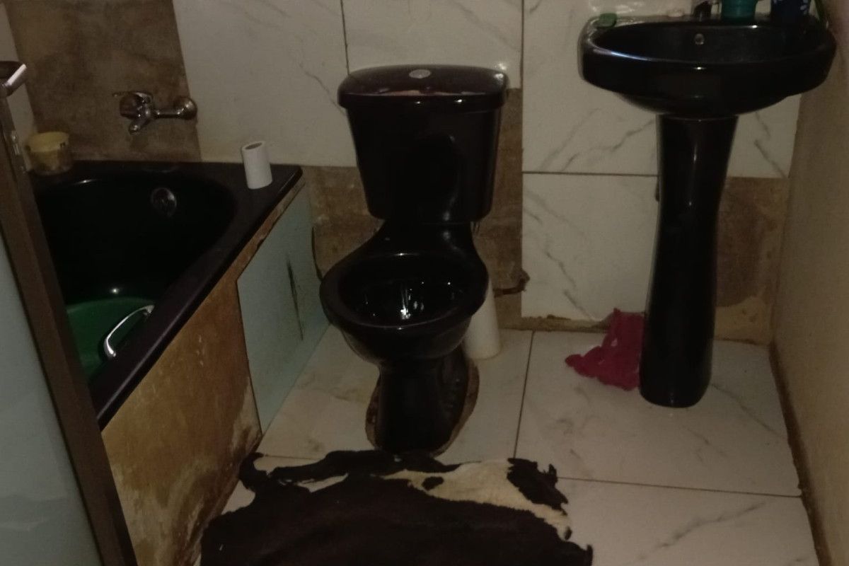 A bathroom featuring black sanitary ware, including a pedestal basin, toilet, and bathtub, with partially tiled walls and floor.
