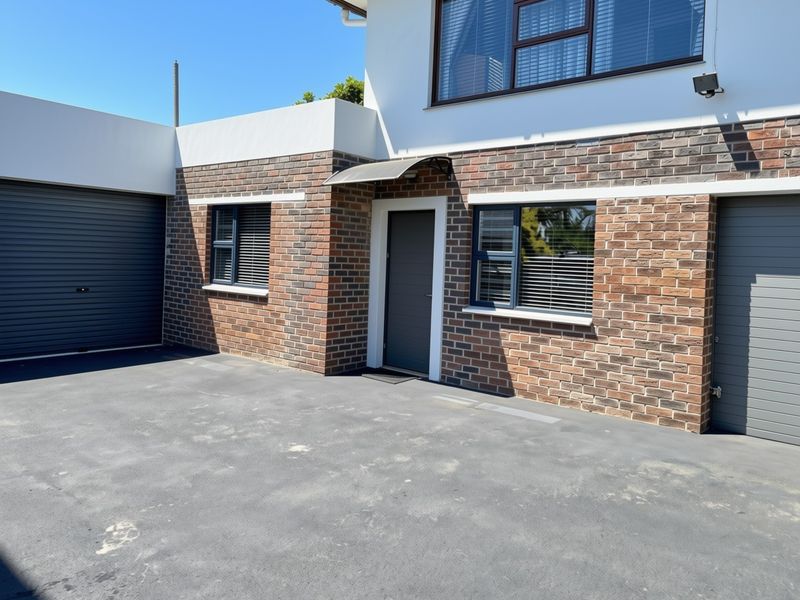 Front exterior view of the apartment featuring a modern brick facade, asphalt driveway, and secure garage access.
