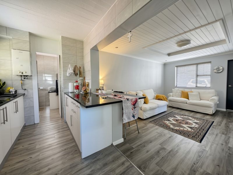 Open-plan living area featuring a modern kitchen with granite countertops, laminate flooring, and a distinctive tongue and groove ceiling design.