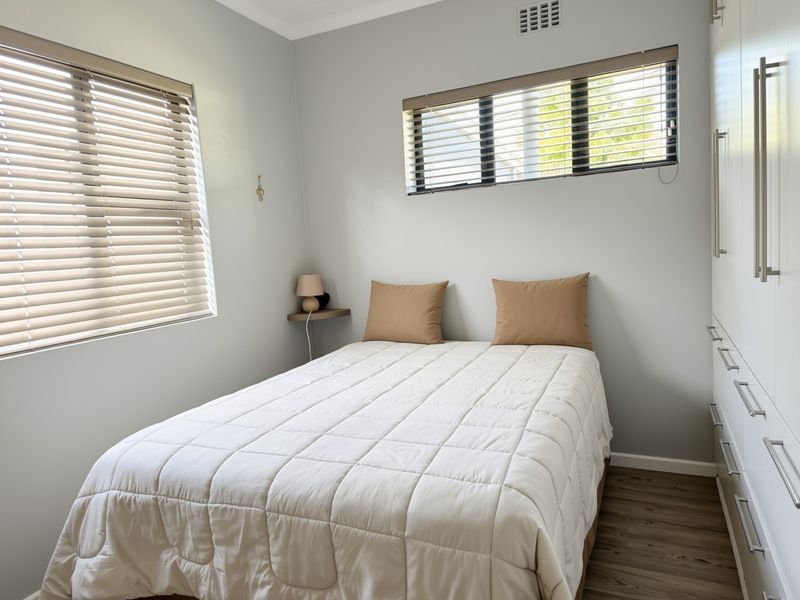 A well-maintained bedroom featuring built-in wardrobes, laminate flooring, and venetian blinds, offering a clean and functional living space.