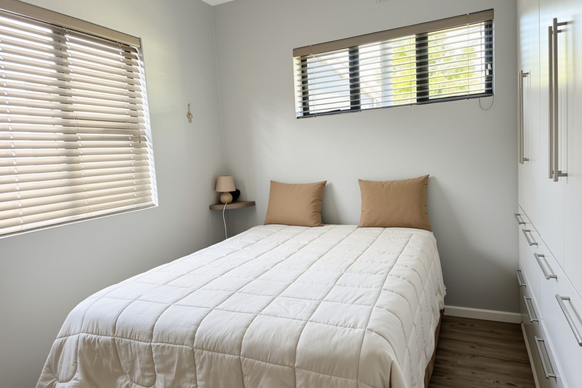 A well-maintained bedroom featuring built-in wardrobes, laminate flooring, and venetian blinds, offering a clean and functional living space.