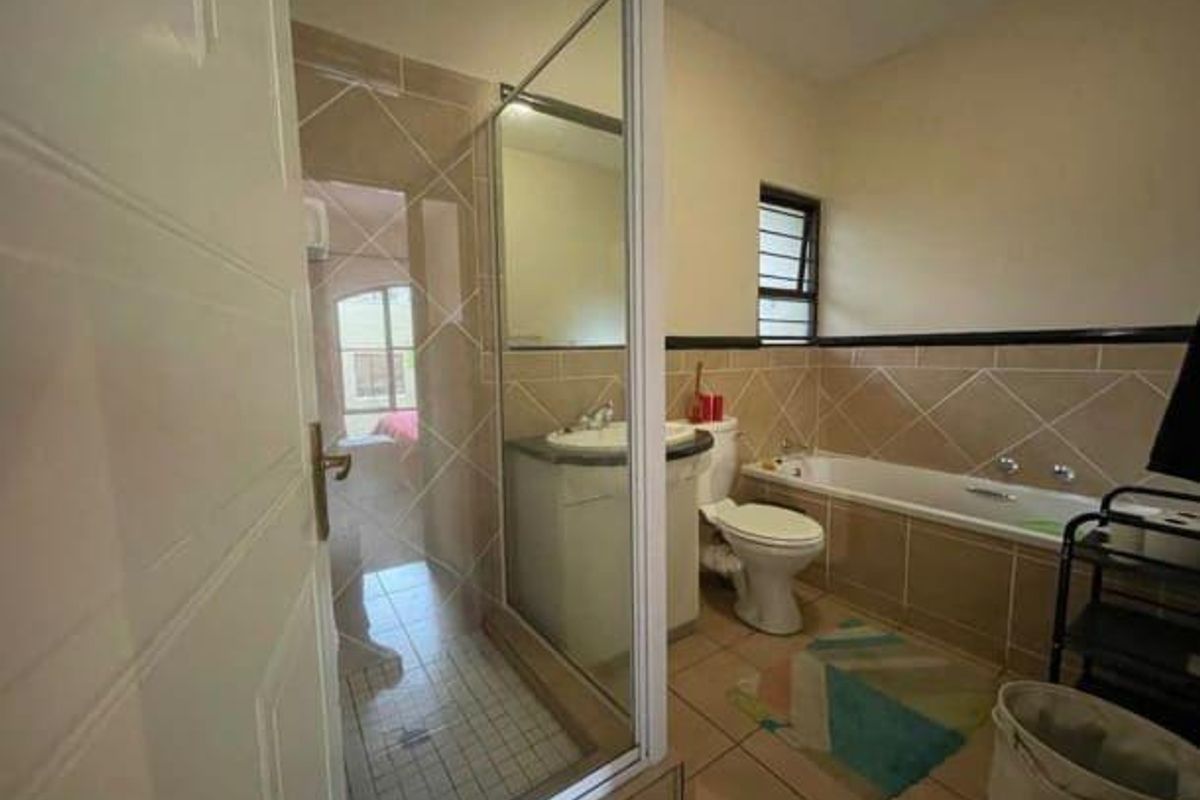 A functional bathroom featuring a separate glass-enclosed shower, a built-in bathtub, and a vanity basin with tiled walls.