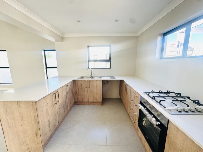 Modern kitchen featuring light wood-grain cabinetry, stone countertops, a gas hob, and a built-in oven in a clean, open-plan layout.