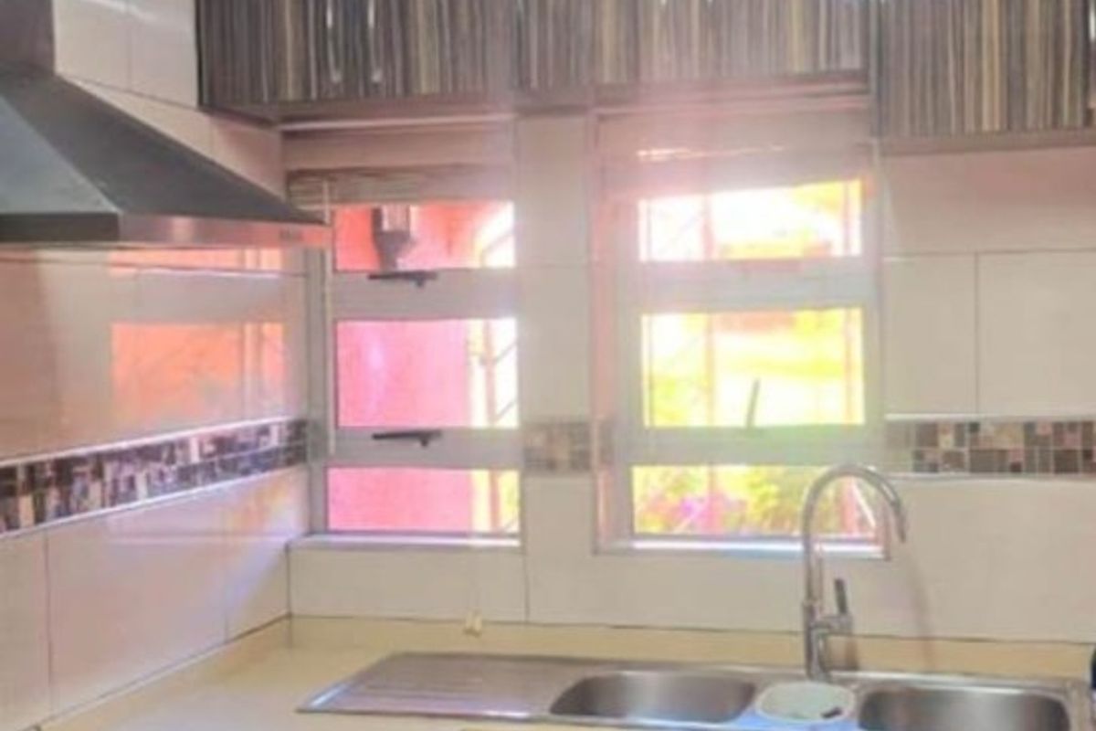 A functional kitchen featuring wood-grain cabinetry, tiled splashbacks, a stainless steel double sink, and a built-in extractor fan.