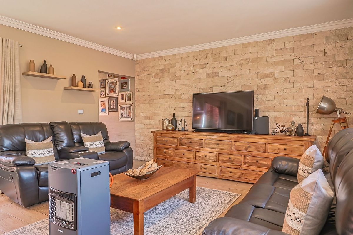 A comfortable living room featuring a textured stone feature wall, tiled flooring, and sliding door access to the outdoor area.