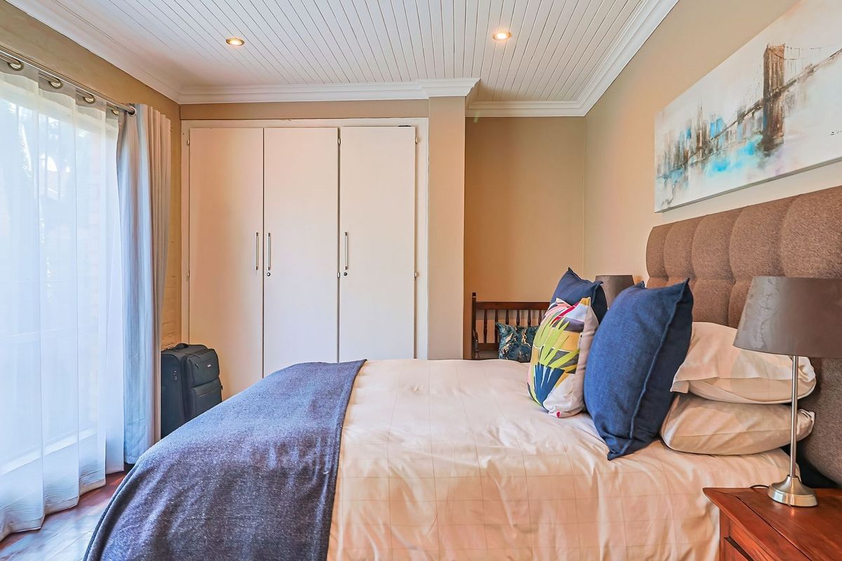 A well-maintained bedroom featuring built-in cupboards, recessed ceiling lighting, and a sliding door providing access to the exterior.