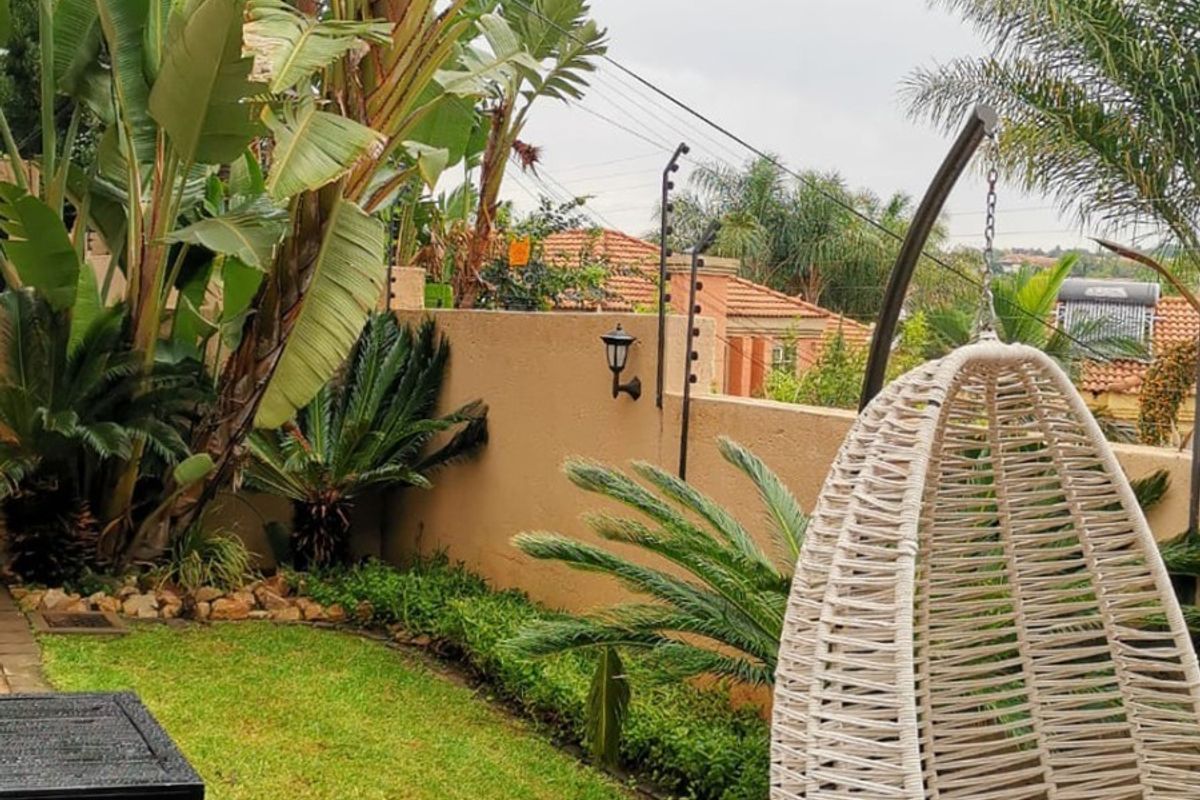 A private rear garden featuring a timber deck, established tropical landscaping, and perimeter walling with integrated security fencing.