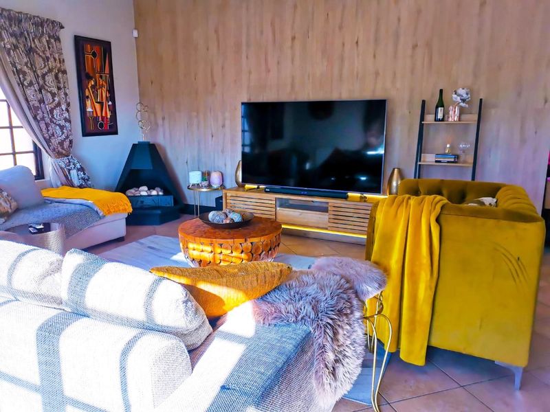 A cozy living room featuring wood-look wall paneling, a corner fireplace, and tiled flooring, creating a warm and inviting atmosphere.