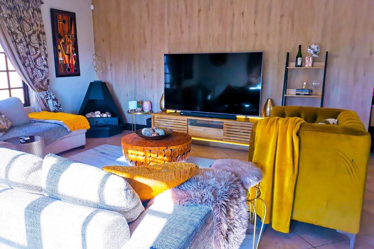 A cozy living room featuring wood-look wall paneling, a corner fireplace, and tiled flooring, creating a warm and inviting atmosphere.