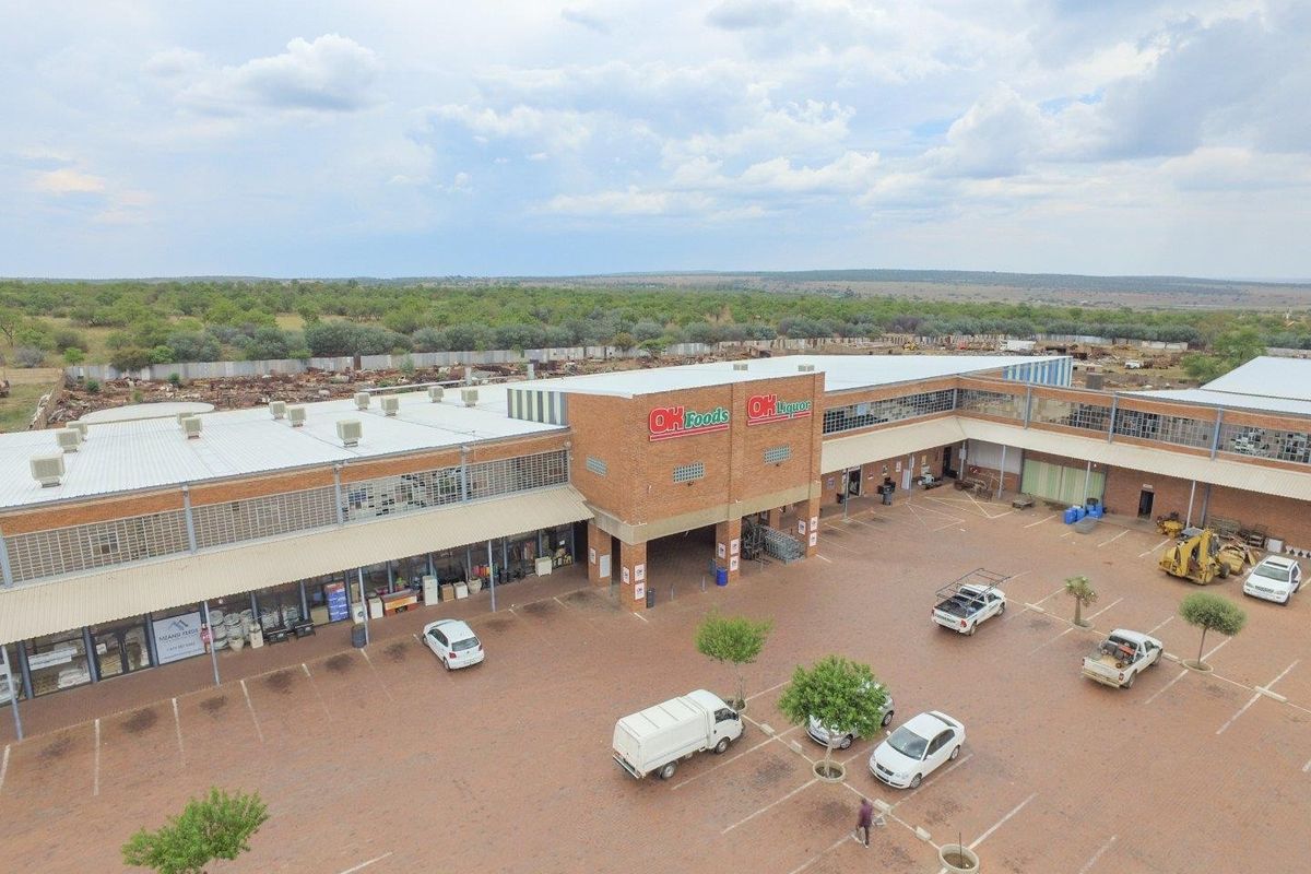 Aerial view of a commercial retail center featuring brick facade, paved parking area, and multiple storefronts with signage.