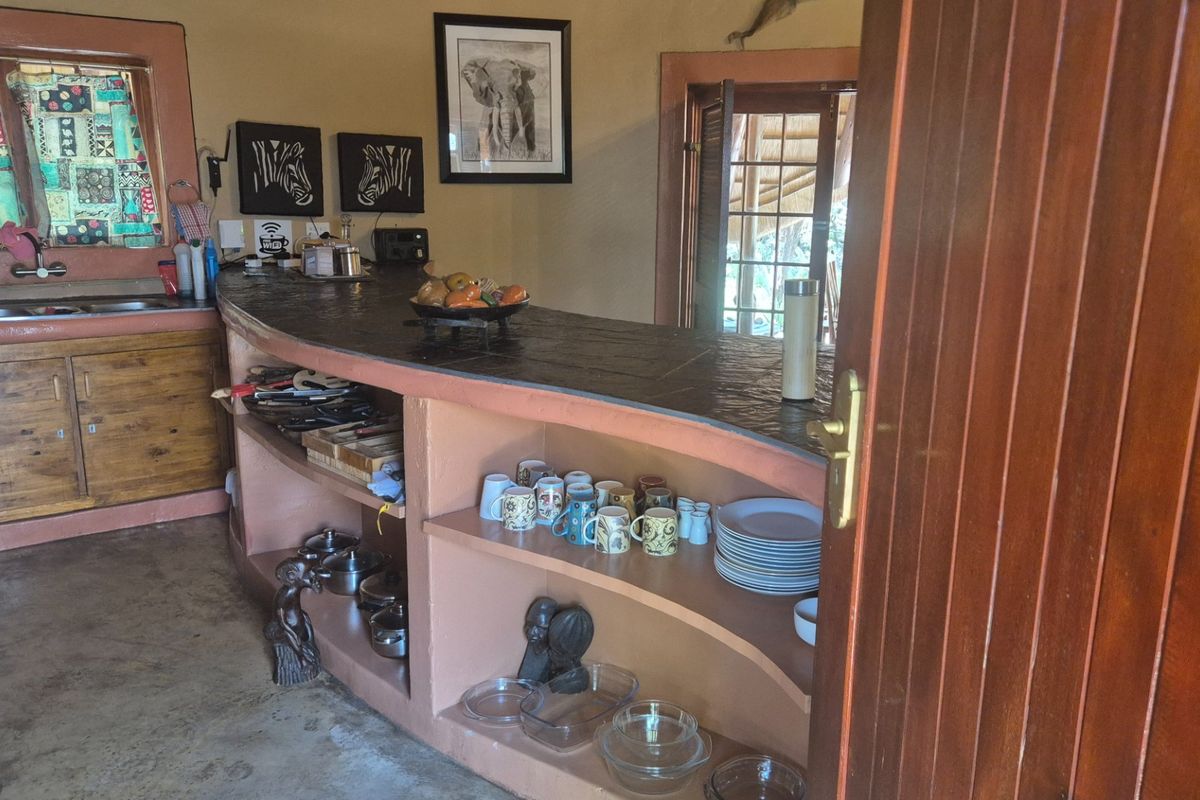 A rustic kitchen featuring a curved built-in masonry breakfast bar with open shelving and a wooden cabinet base.