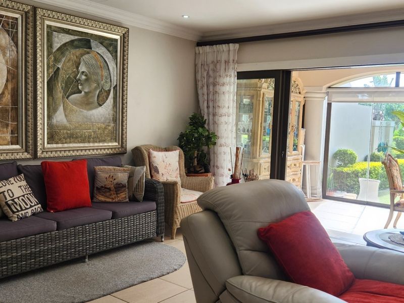 A comfortable living room featuring tiled flooring, recessed downlights, and large sliding glass doors that provide seamless access to the outdoor patio area.