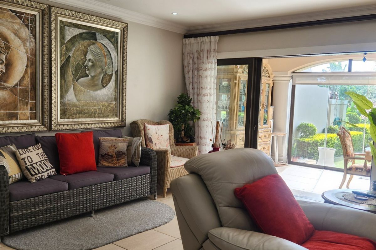 A comfortable living room featuring tiled flooring, recessed downlights, and large sliding glass doors that provide seamless access to the outdoor patio area.