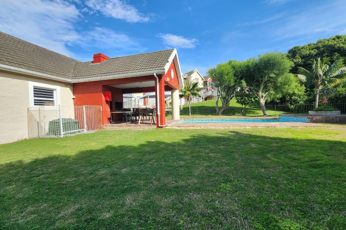 A spacious backyard featuring a covered patio area, a swimming pool, and a well-maintained lawn, perfect for outdoor relaxation and entertainment.
