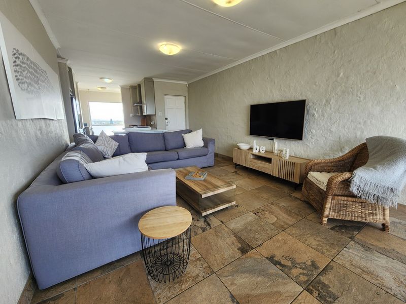 Open plan living area featuring textured walls, tiled flooring, and a seamless transition to the kitchen space.