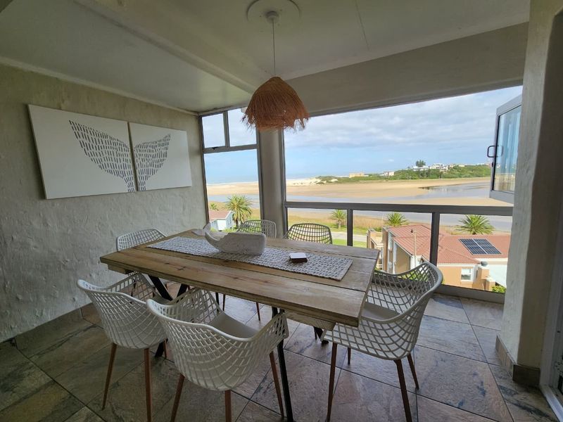 Enclosed balcony featuring large windows with scenic coastal and river views, tiled flooring, and a covered ceiling structure.