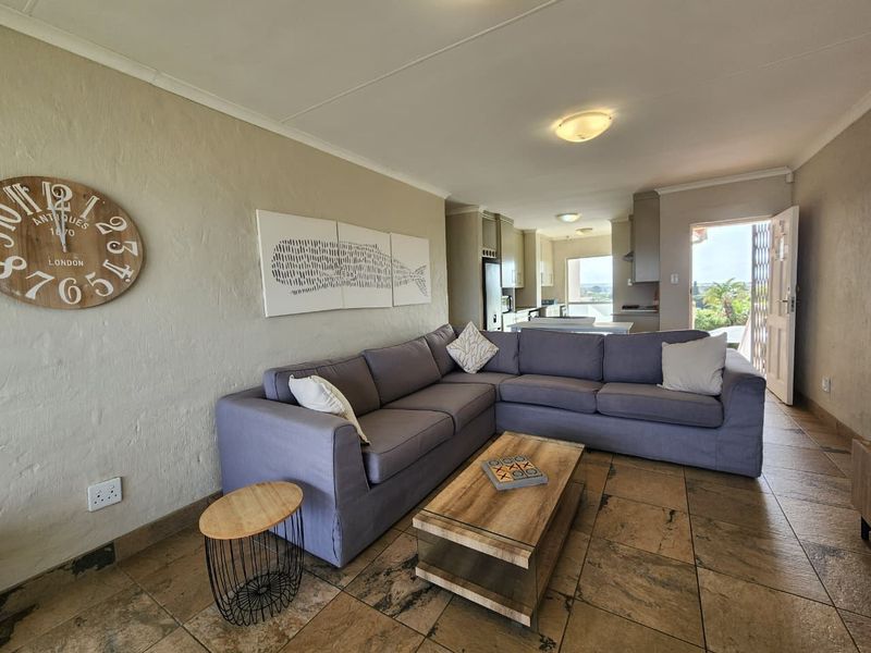 Open plan living area featuring tiled flooring, neutral walls, and direct access to an outdoor balcony, seamlessly flowing into the kitchen space.