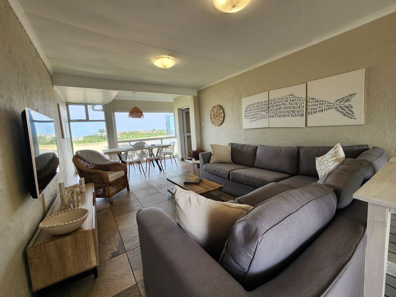 Open plan living and dining area featuring tiled flooring and large windows with natural light, creating a seamless flow to the outdoor space.