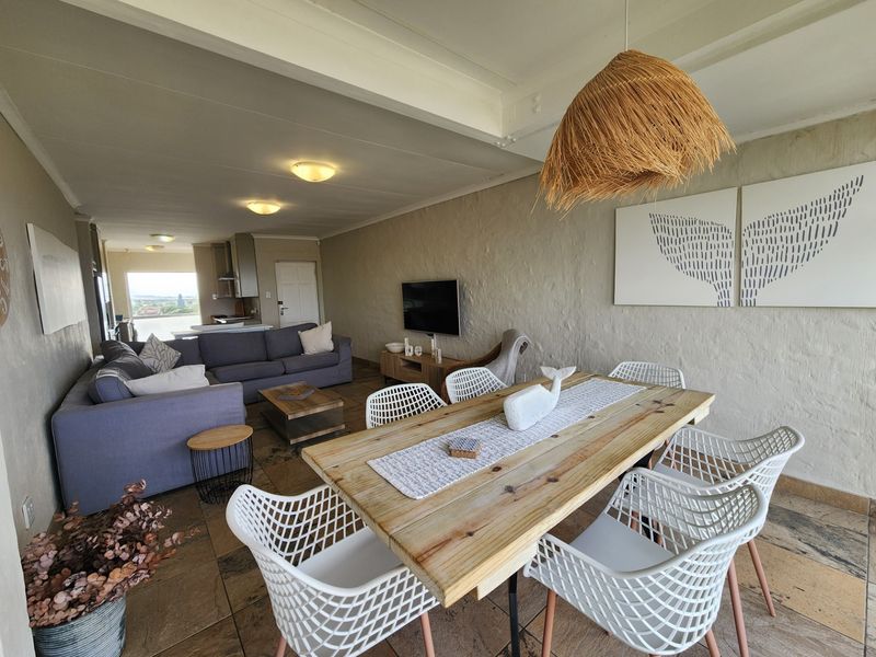 Spacious open-plan living and dining area featuring tiled flooring, textured walls, and a seamless flow to the kitchen and outdoor view.
