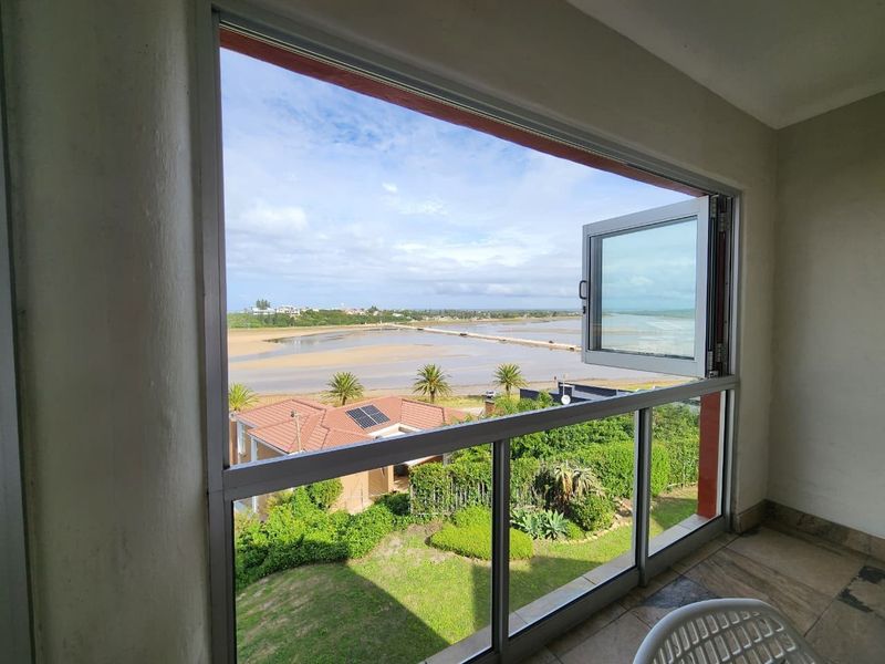 A balcony featuring large glass windows that provide an expansive, scenic view of the surrounding landscape and estuary.