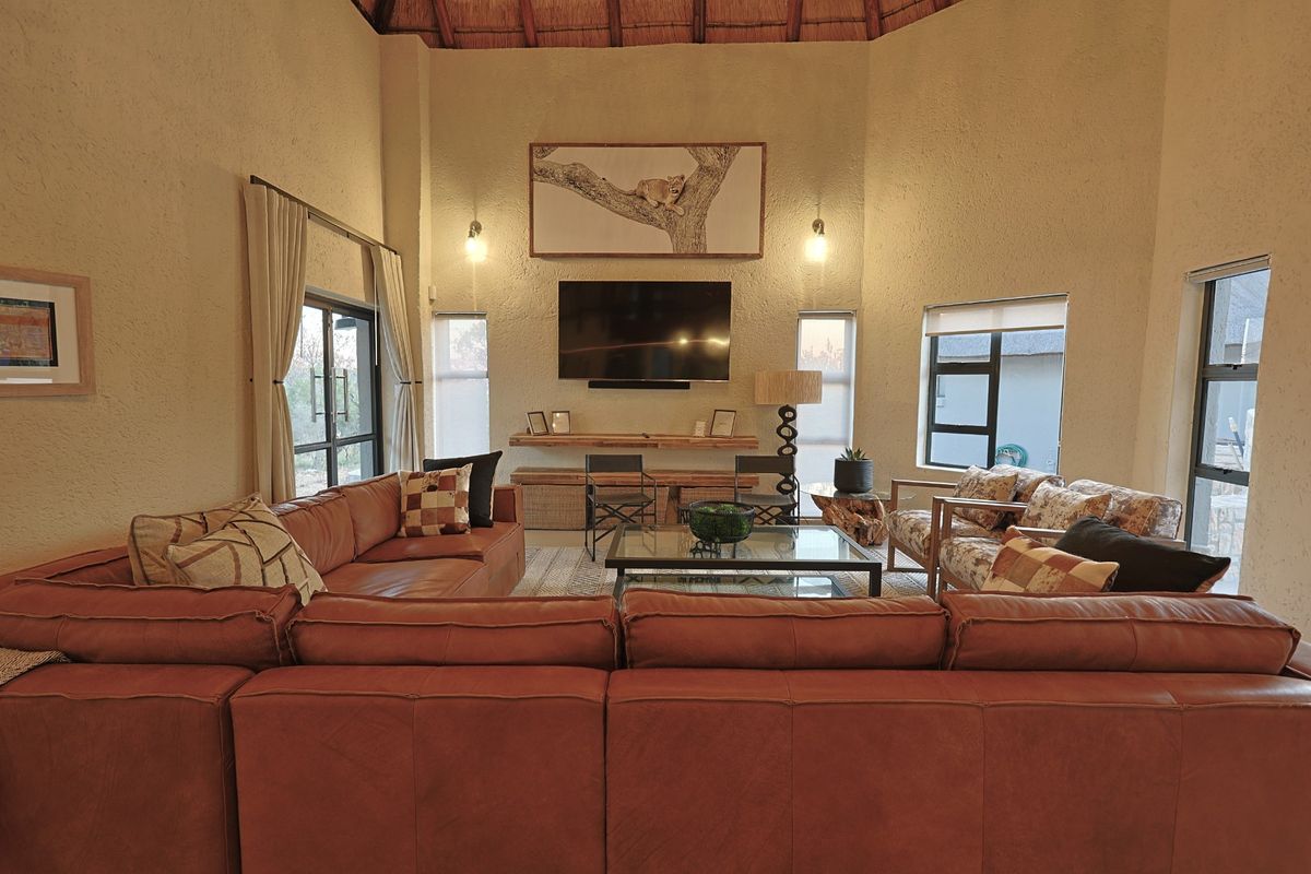 Spacious living room featuring a high vaulted thatched ceiling, textured walls, and large windows that provide ample natural light.