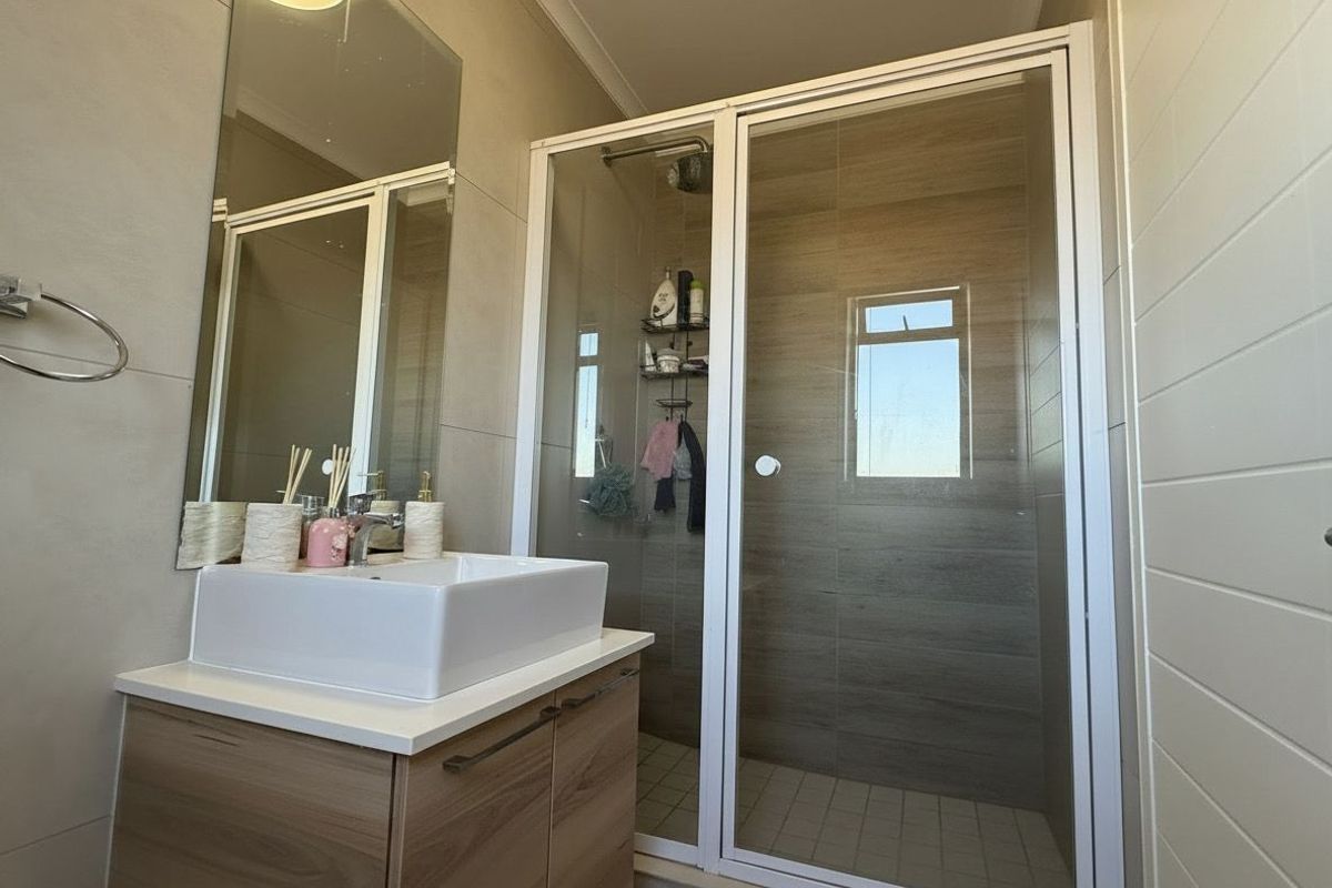 Modern bathroom featuring a vessel sink vanity, large wall mirror, and a glass-enclosed shower with tiled walls.