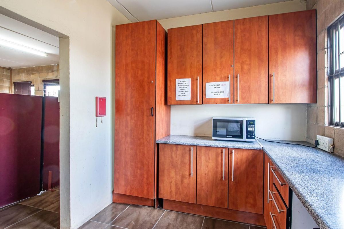 Functional industrial kitchen area featuring laminate cabinetry, durable countertops, and tiled flooring, suitable for staff use.