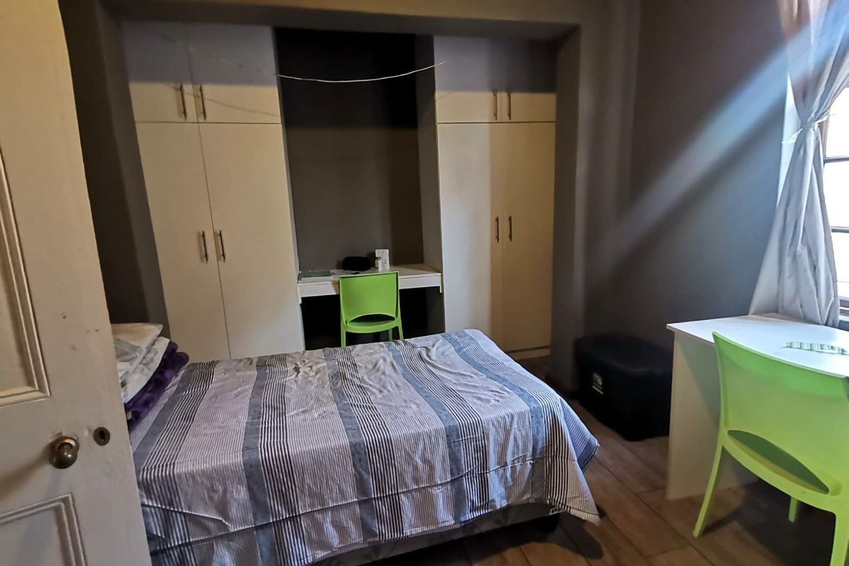 A bedroom featuring built-in cupboards with an integrated desk area and tiled flooring.