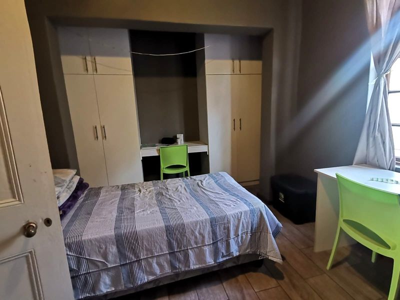 A bedroom featuring built-in cupboards with an integrated desk area and tiled flooring.
