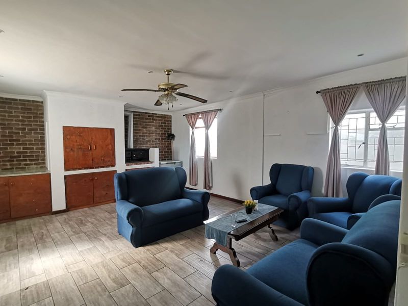 Spacious living room featuring tiled flooring, a built-in brick fireplace, and a ceiling fan, offering a comfortable and functional layout.