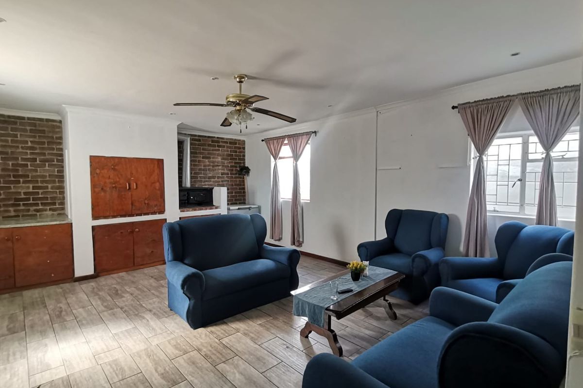 Spacious living room featuring tiled flooring, a built-in brick fireplace, and a ceiling fan, offering a comfortable and functional layout.