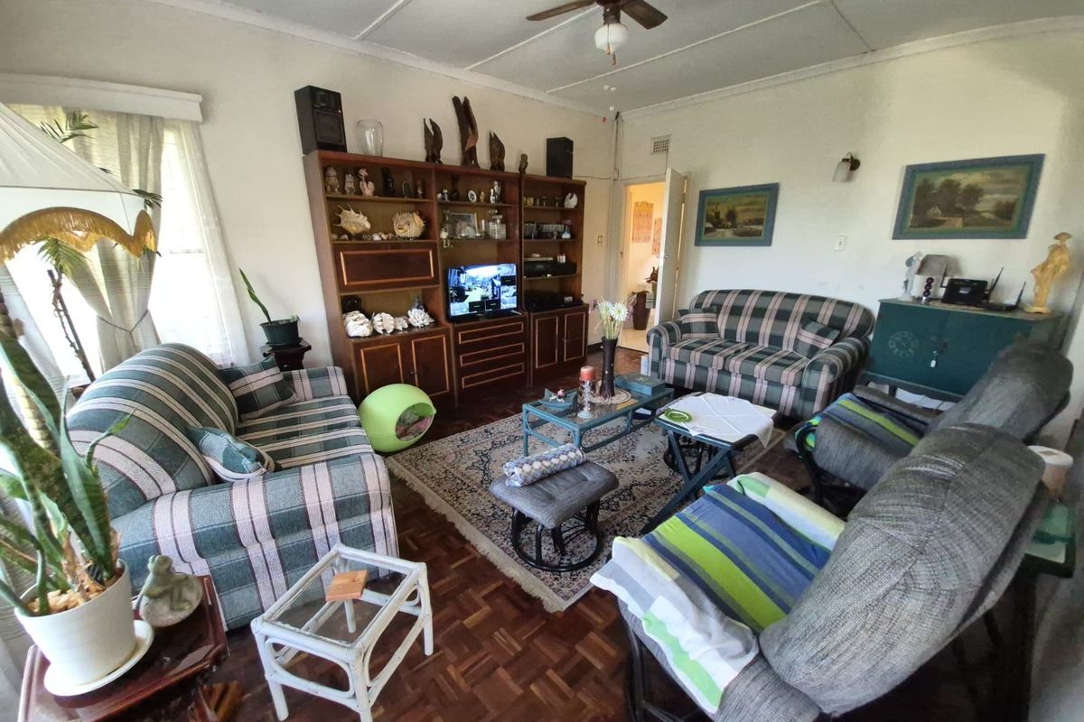 A traditional living room featuring original parquet wood flooring, a ceiling fan, and built-in shelving, offering a classic and functional living space.
