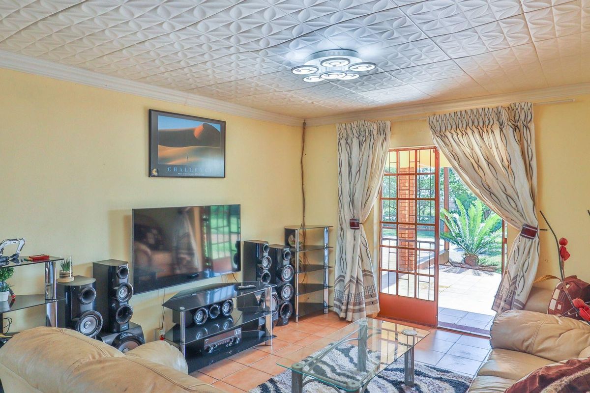 A living room featuring tiled flooring, a decorative ceiling, and a glass door providing direct access to the outdoor patio area.