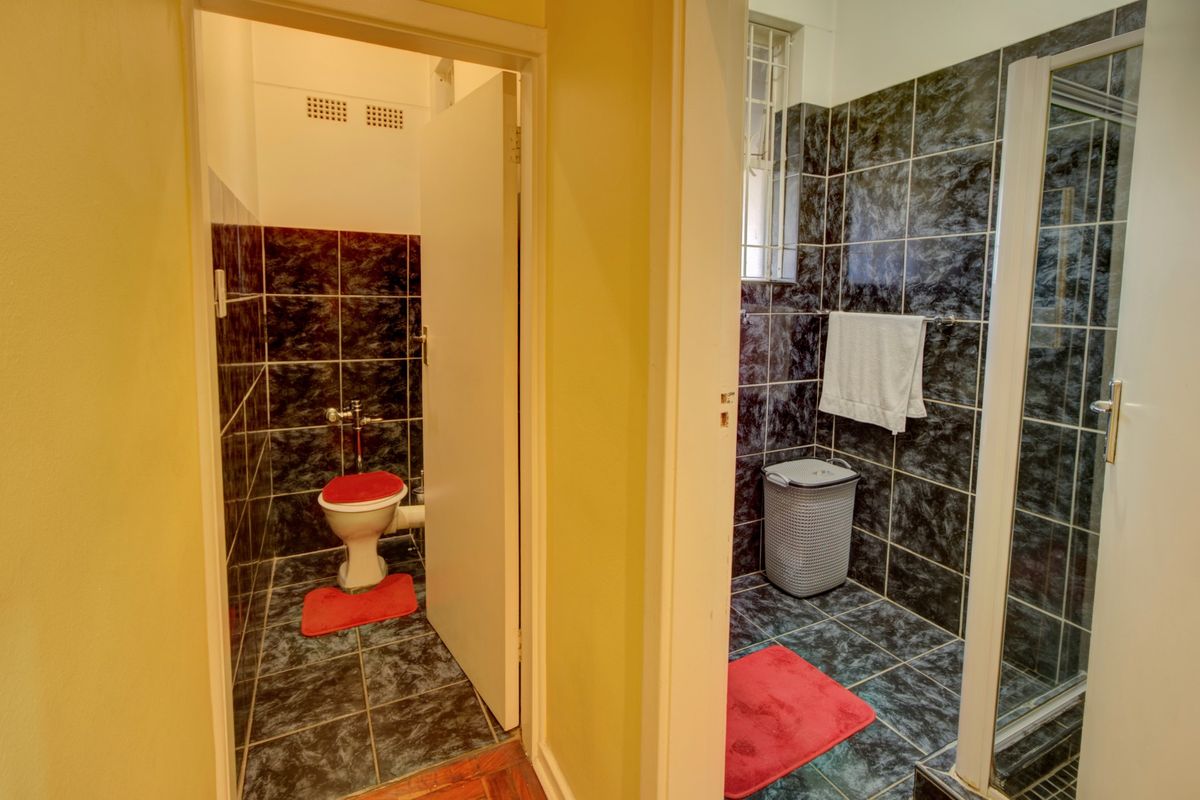 A functional bathroom featuring a separate toilet and shower area with dark marble-effect wall and floor tiles.