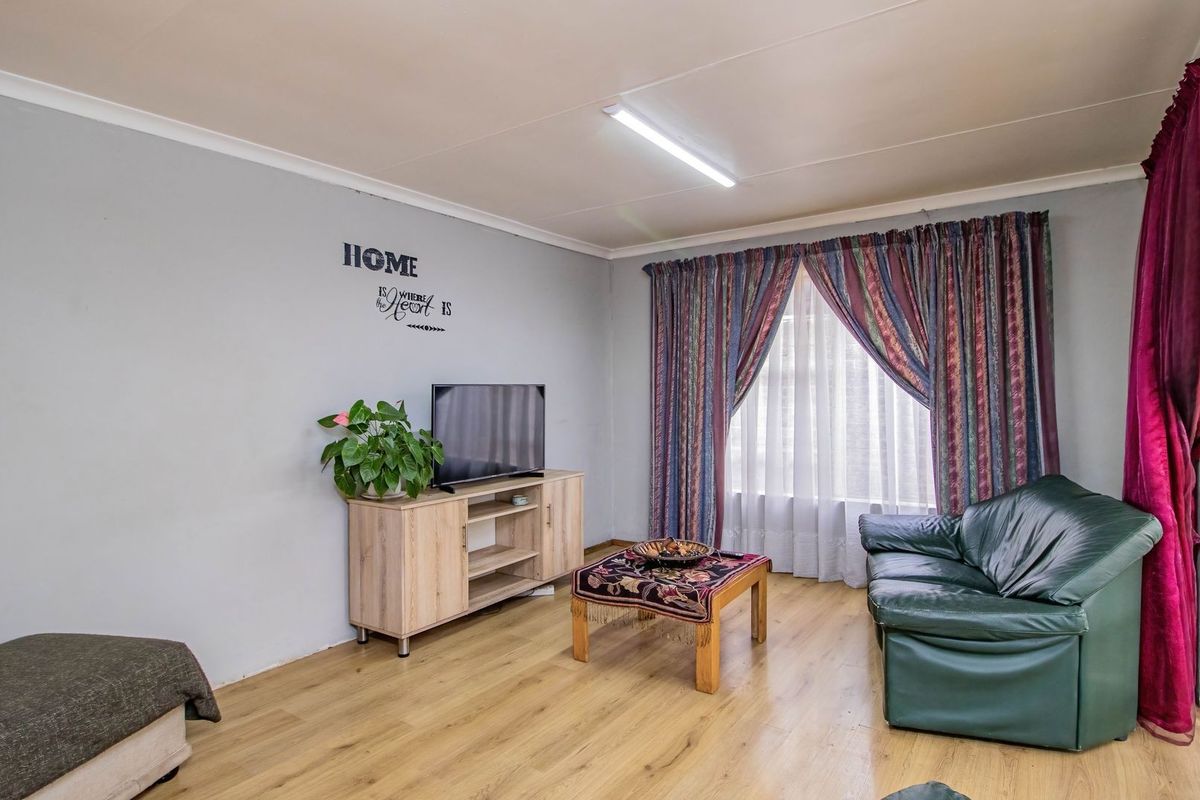 A living room featuring laminate flooring and a security gate, providing a functional and neutral space for relaxation.