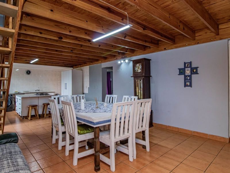 Open plan living and dining area featuring exposed timber beam ceilings, tiled flooring, and an integrated kitchen with a central island.
