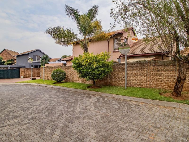 Street view showing the paved driveway, brick boundary wall, and exterior facade of the residential property.