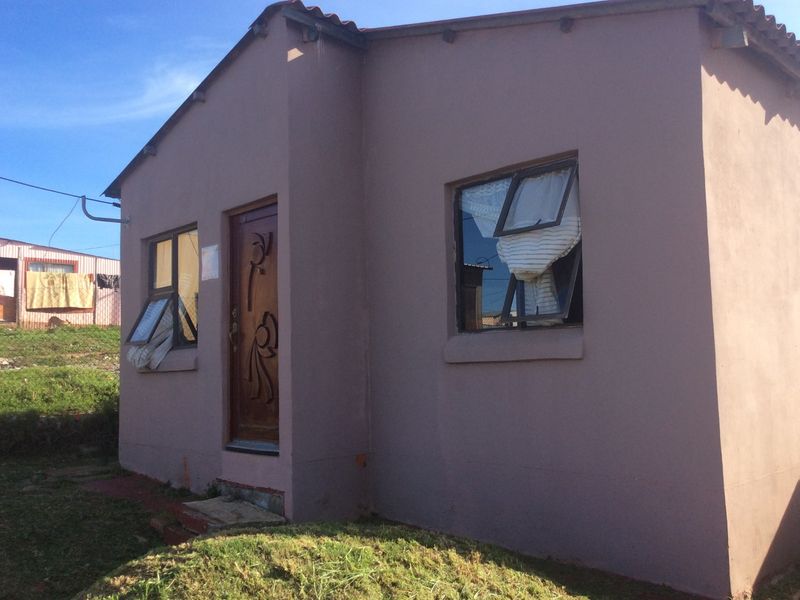 A modest single-story residential dwelling featuring a painted exterior, timber entrance door, and top-hung window frames.