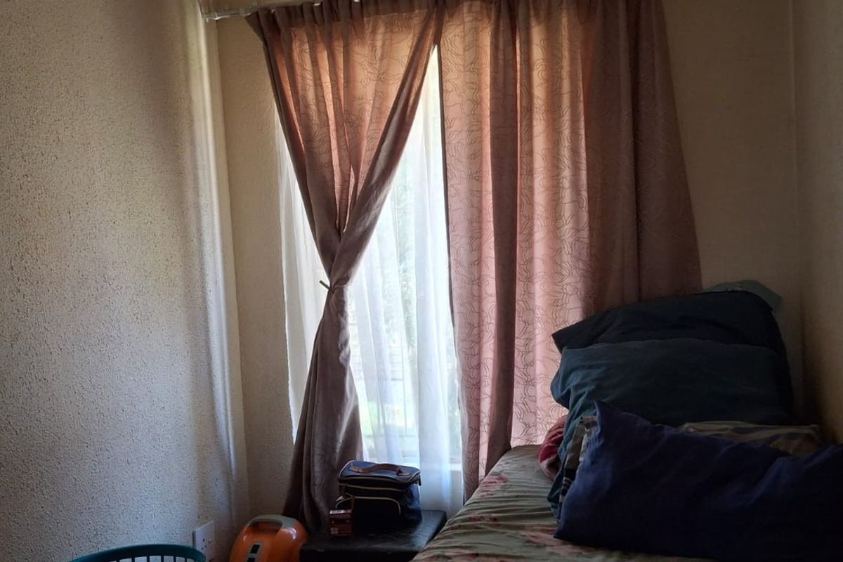 A compact bedroom featuring a window with curtains and standard interior finishes.
