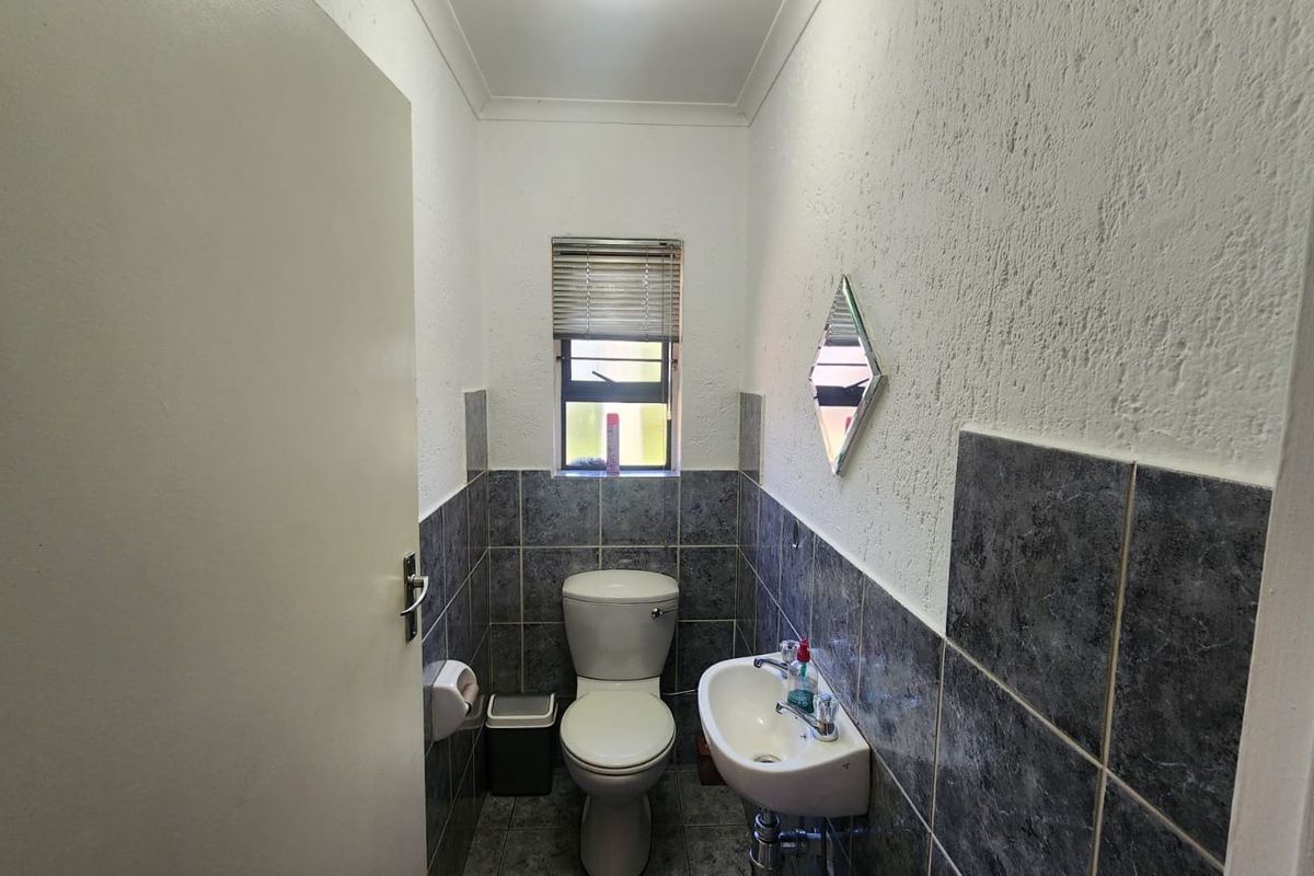 A compact guest bathroom featuring a wall-mounted basin, toilet, and dark grey tiled finishes.