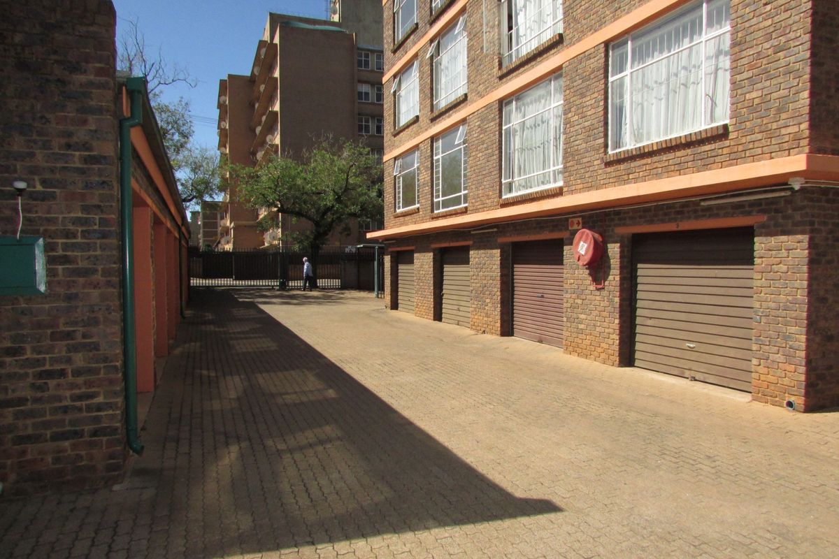 Exterior view of the apartment complex featuring a paved driveway and multiple secure lock-up garages.