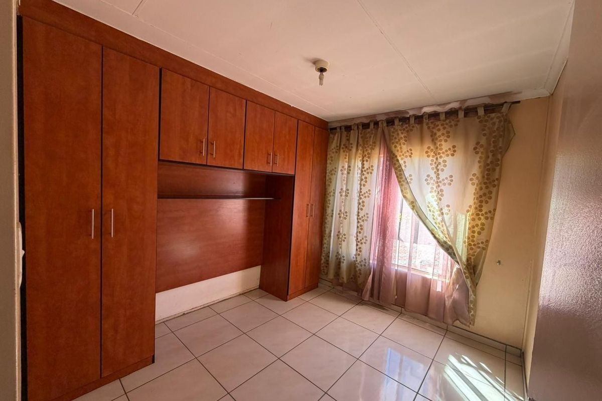 A bedroom featuring built-in wooden cabinetry and tiled flooring, offering functional storage space.