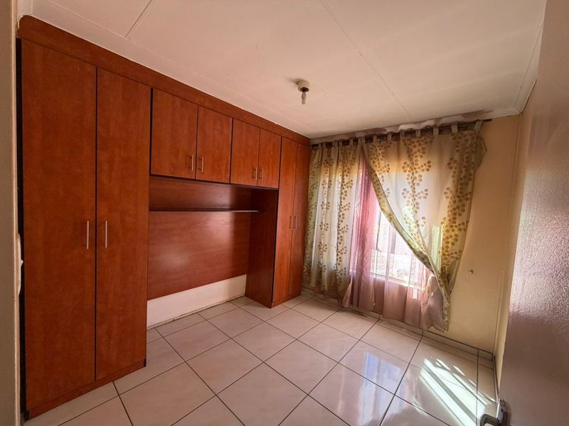 A bedroom featuring built-in wooden cabinetry and tiled flooring, offering functional storage space.
