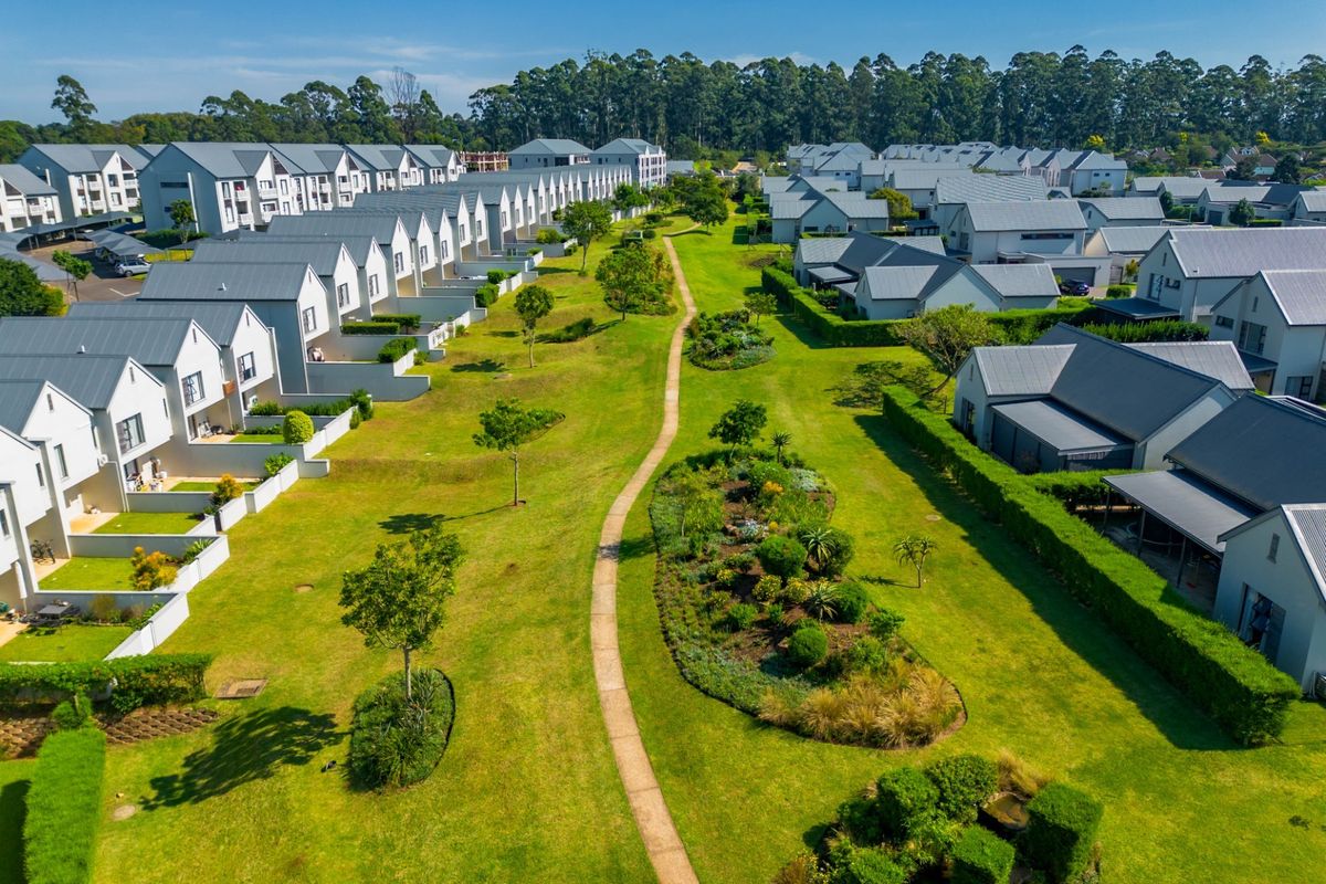 Aerial view of a modern residential apartment complex featuring uniform architecture, manicured green spaces, and landscaped walking paths.